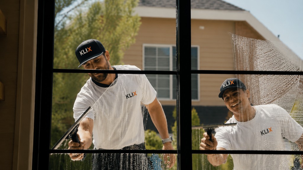 Two Klix technicians cleaning a Thunder Bay window from opposite sides of the glass